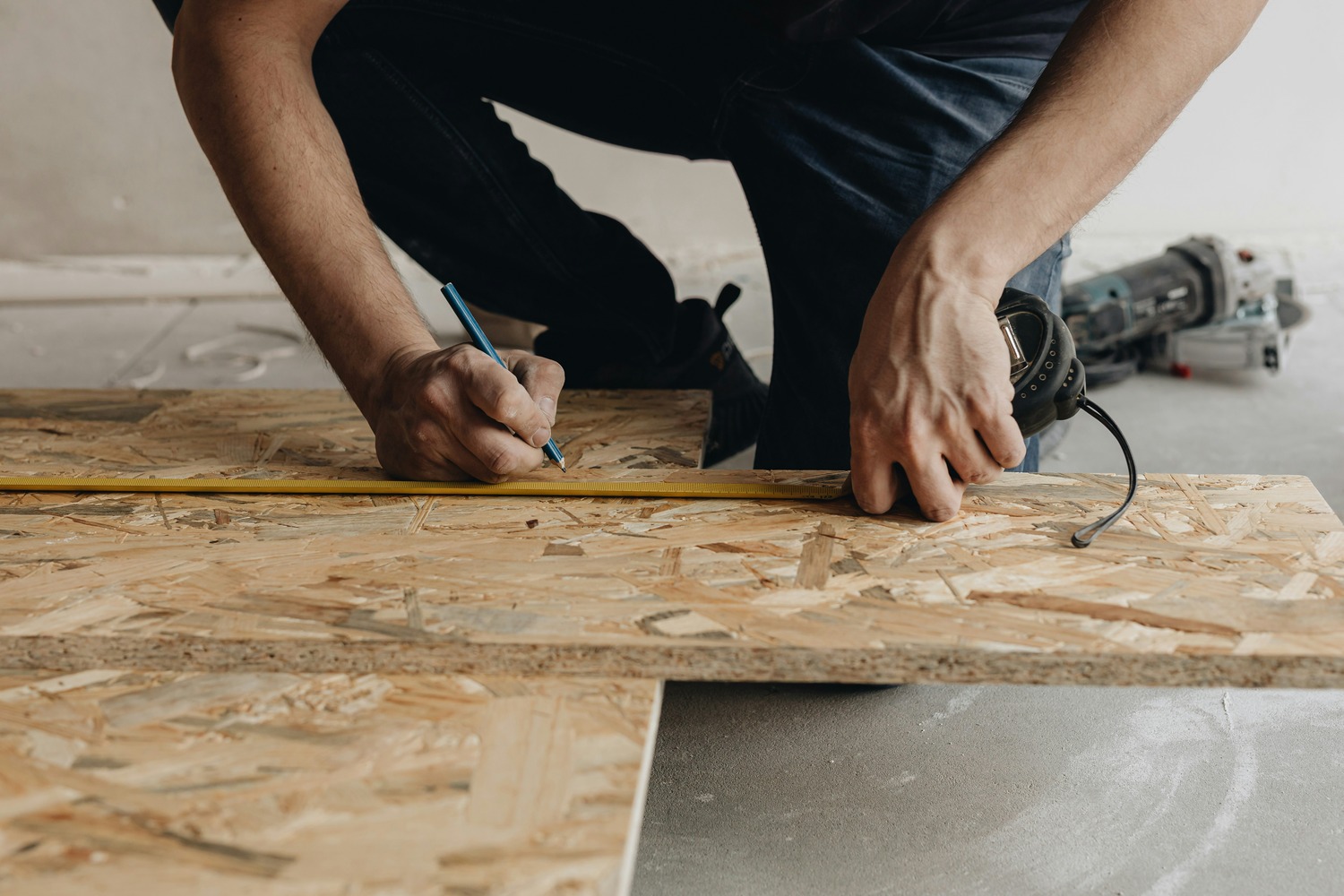 Contractor measuring and cutting subfloor board for a mobile home repair